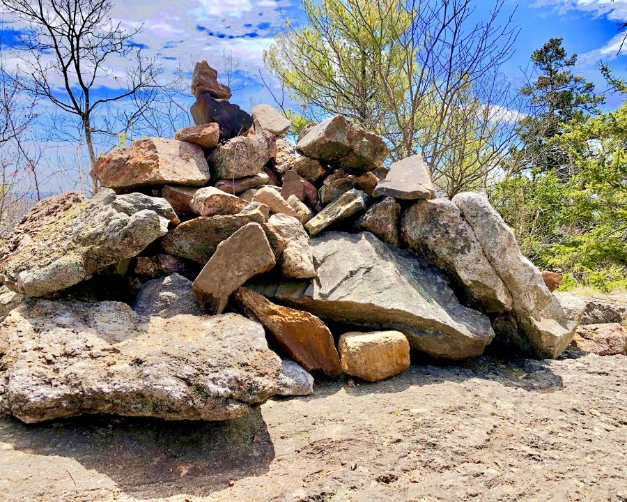 cairn with trees and blue sky in background
