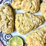 four glazed scones on an elegant plate garnished with a slice of lime