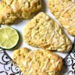 four glazed scones on an elegant plate garnished with a slice of lime