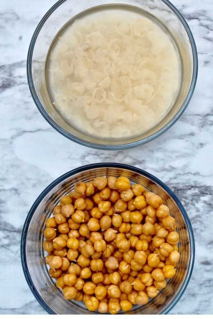 2 bowls - one with chickpea skins in water, one with peeled chickpeas