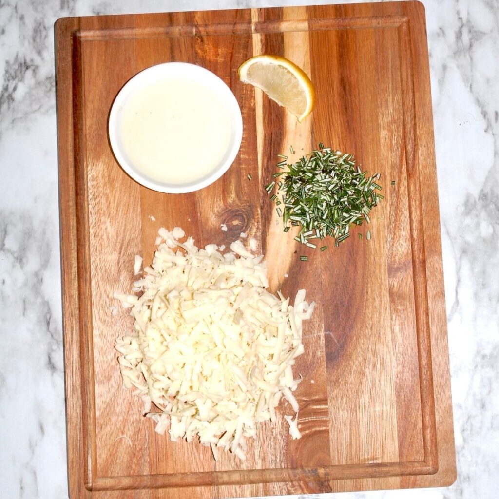 shredded cheese, finely chopped rosemary and lemon juice on a wooden cutting board