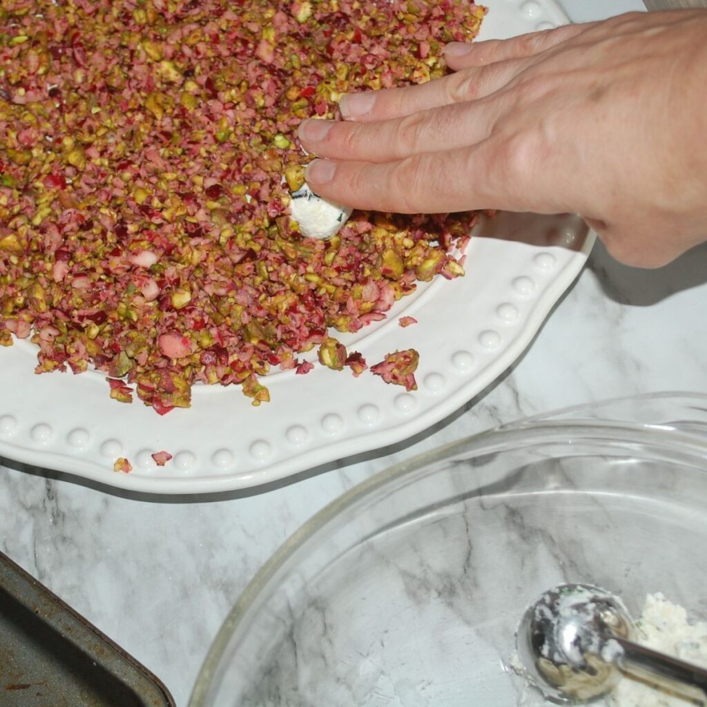 rolling cheese ball in cranberries and pistachios