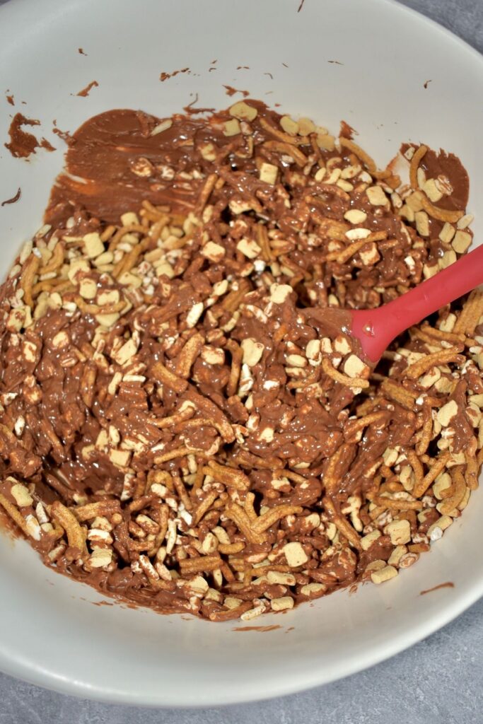 mixing melted chocolate with whole grain cereal with red spoon