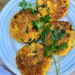 4 chickpea patties on a white plate garnished with fresh parsley
