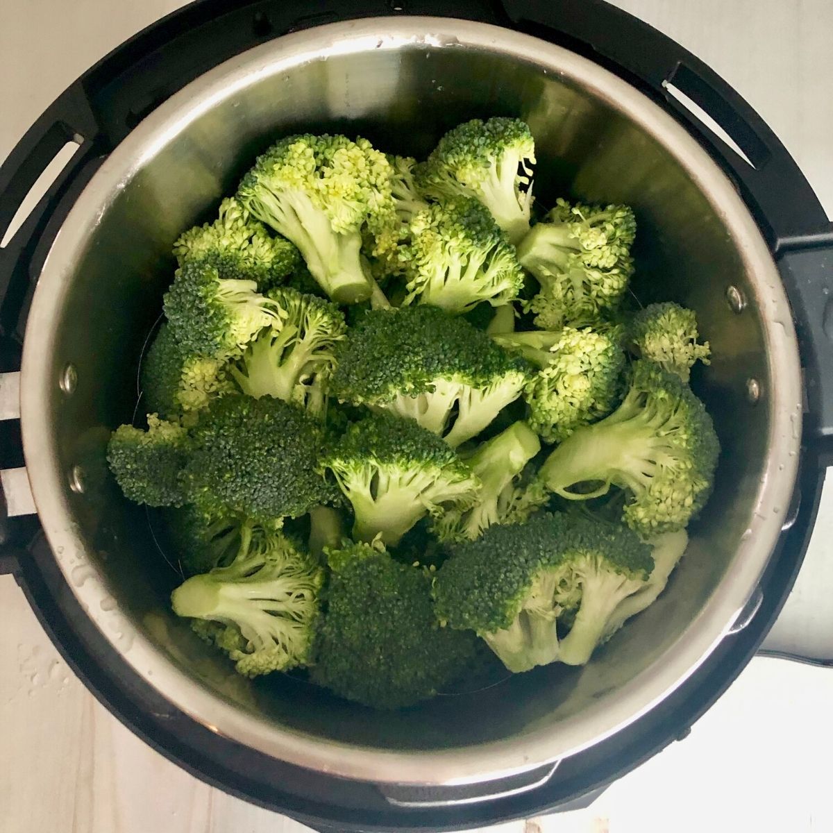 an Instant Pot filled with raw broccoli florets.