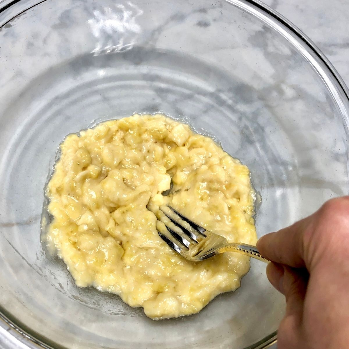 Mashed Banana in a glass mixing bowl.