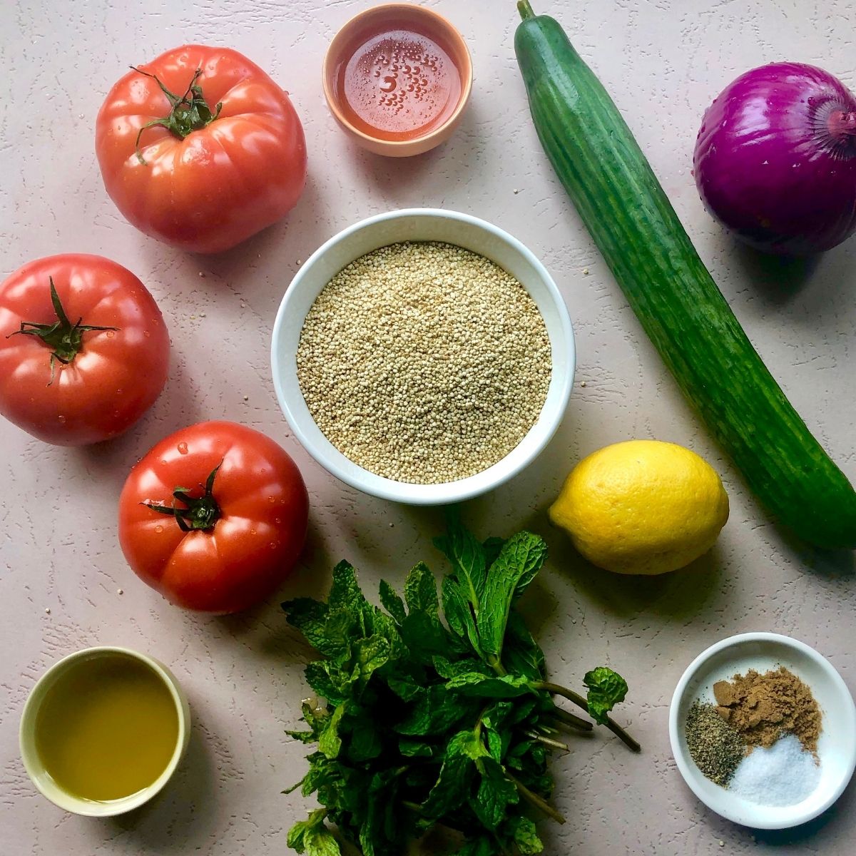 3 tomatoes, 1 cuke, 1 red onion, 1 lemon, handful of fresh mint leaves, bowl of quinoa, small bowls of olive oil, vinegar, and spices