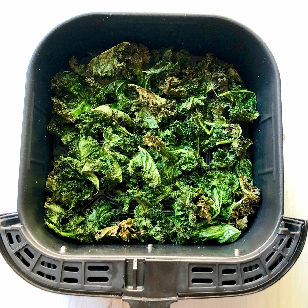 crispy, browned kale chips in an air fryer basket.