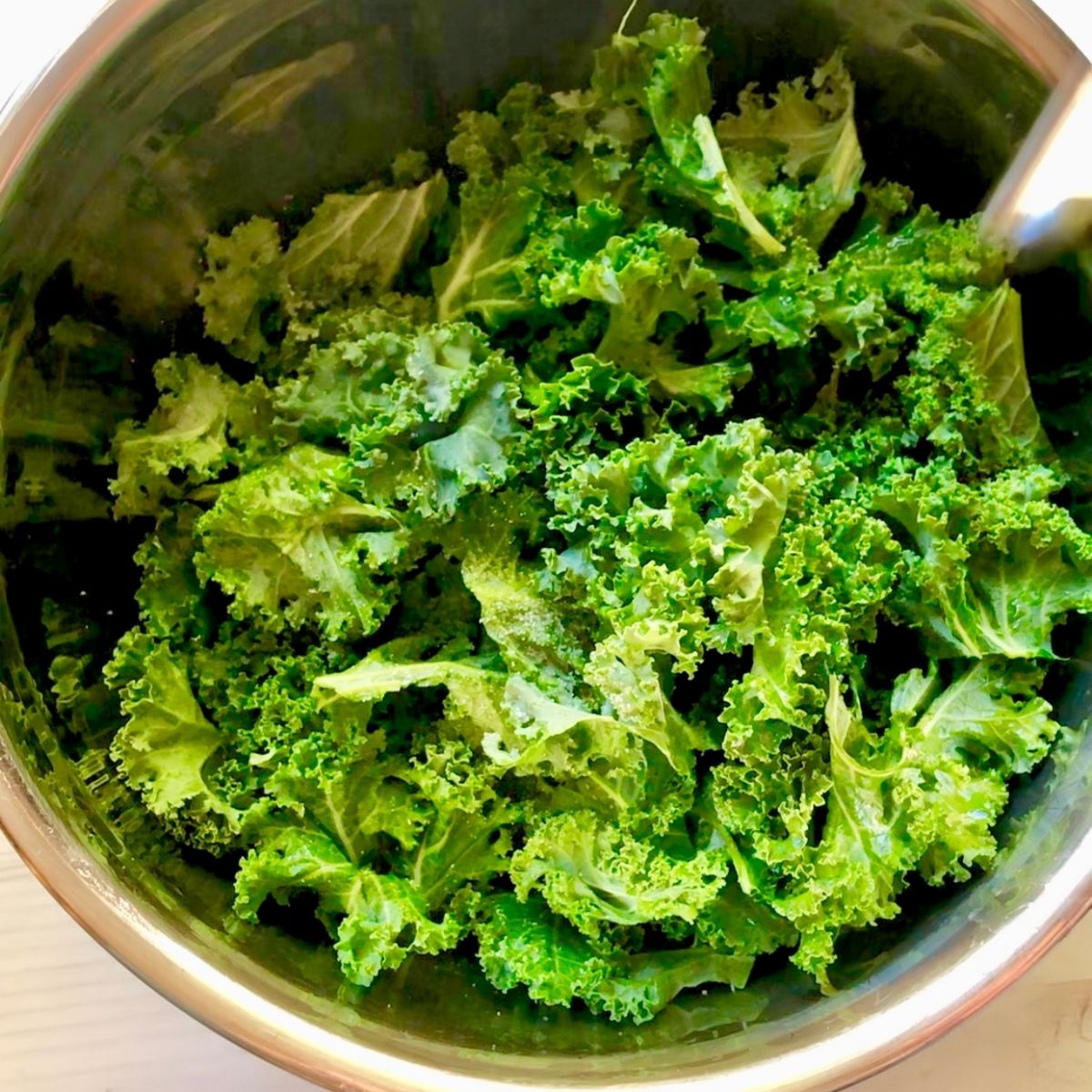 bowl of kale leaves massaged with olive oil and salt.