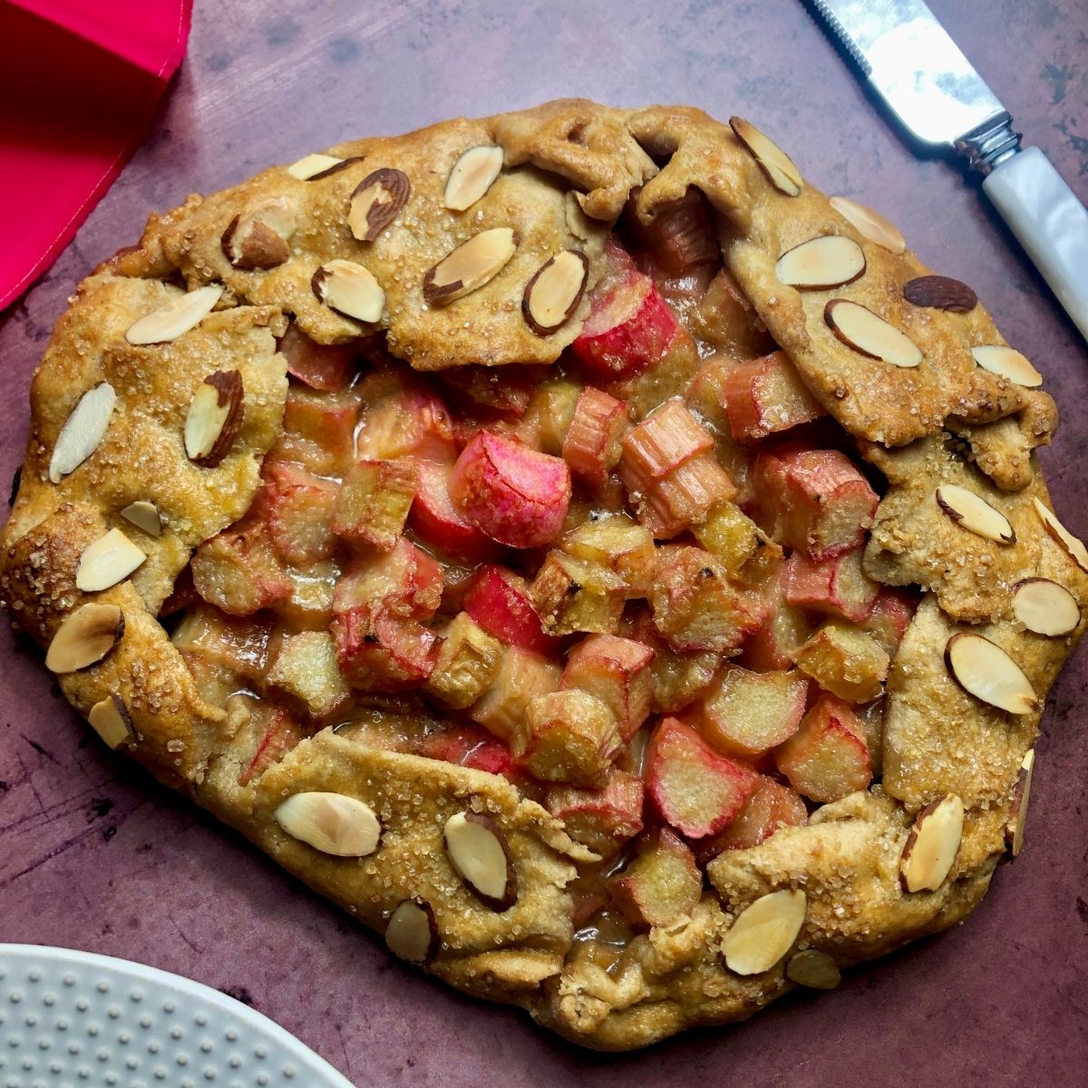 a rhubarb galette garnished with sliced almonds on crust