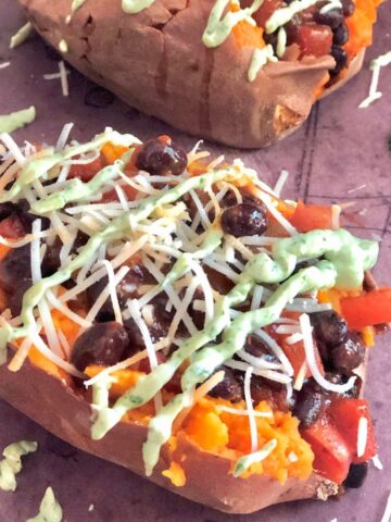 two sweet potatoes stuffed with black beans, salsa, cheese, and avocado sauce.
