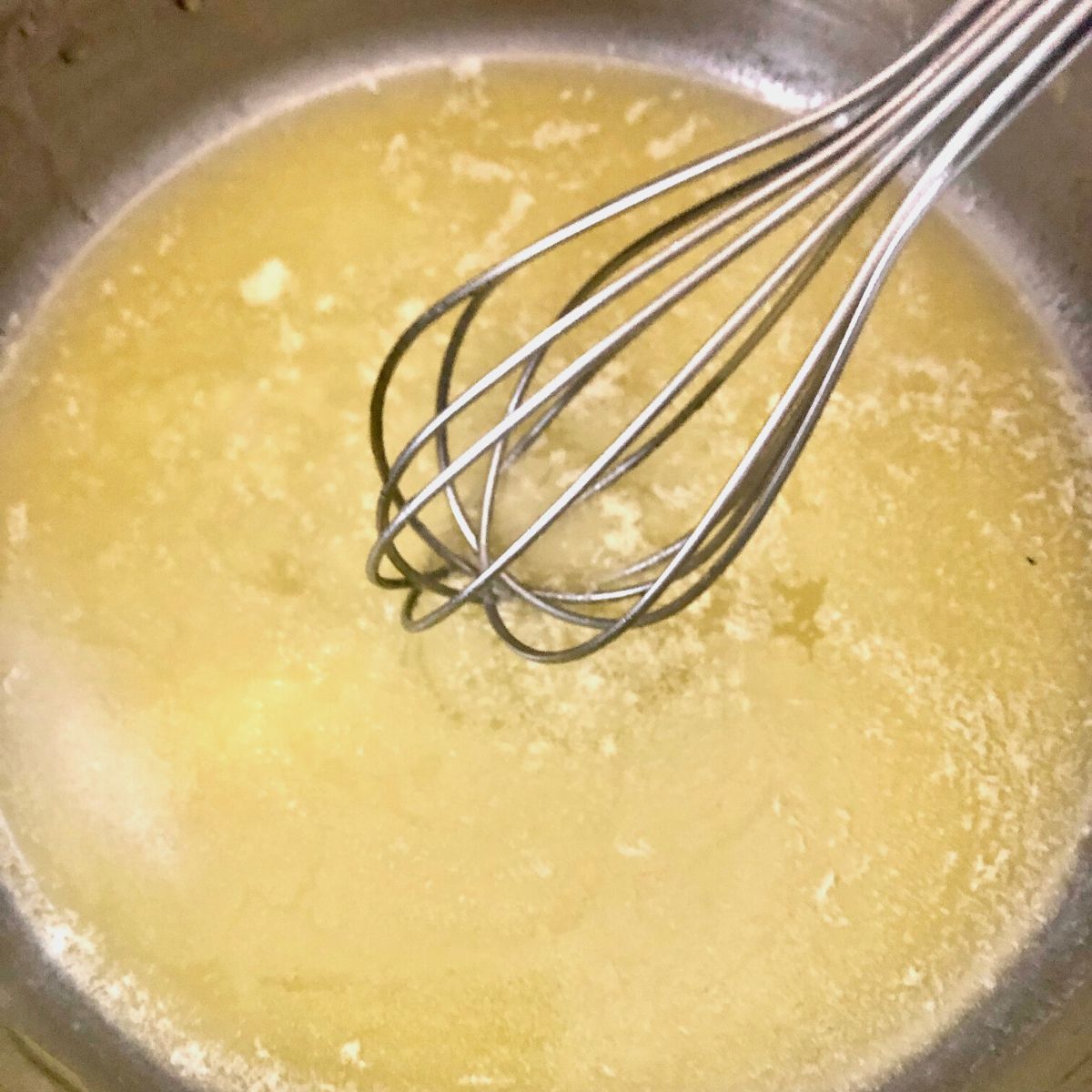Melted butter in a saucepan with metal whisk
