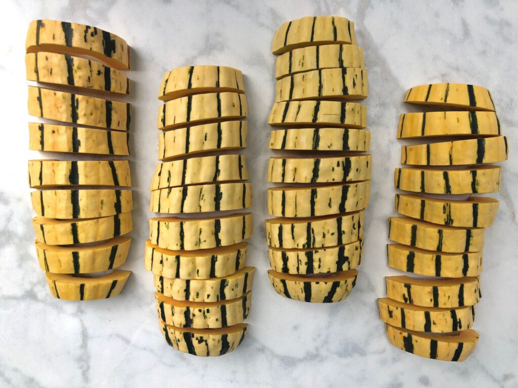 two halved delicata squashes sliced