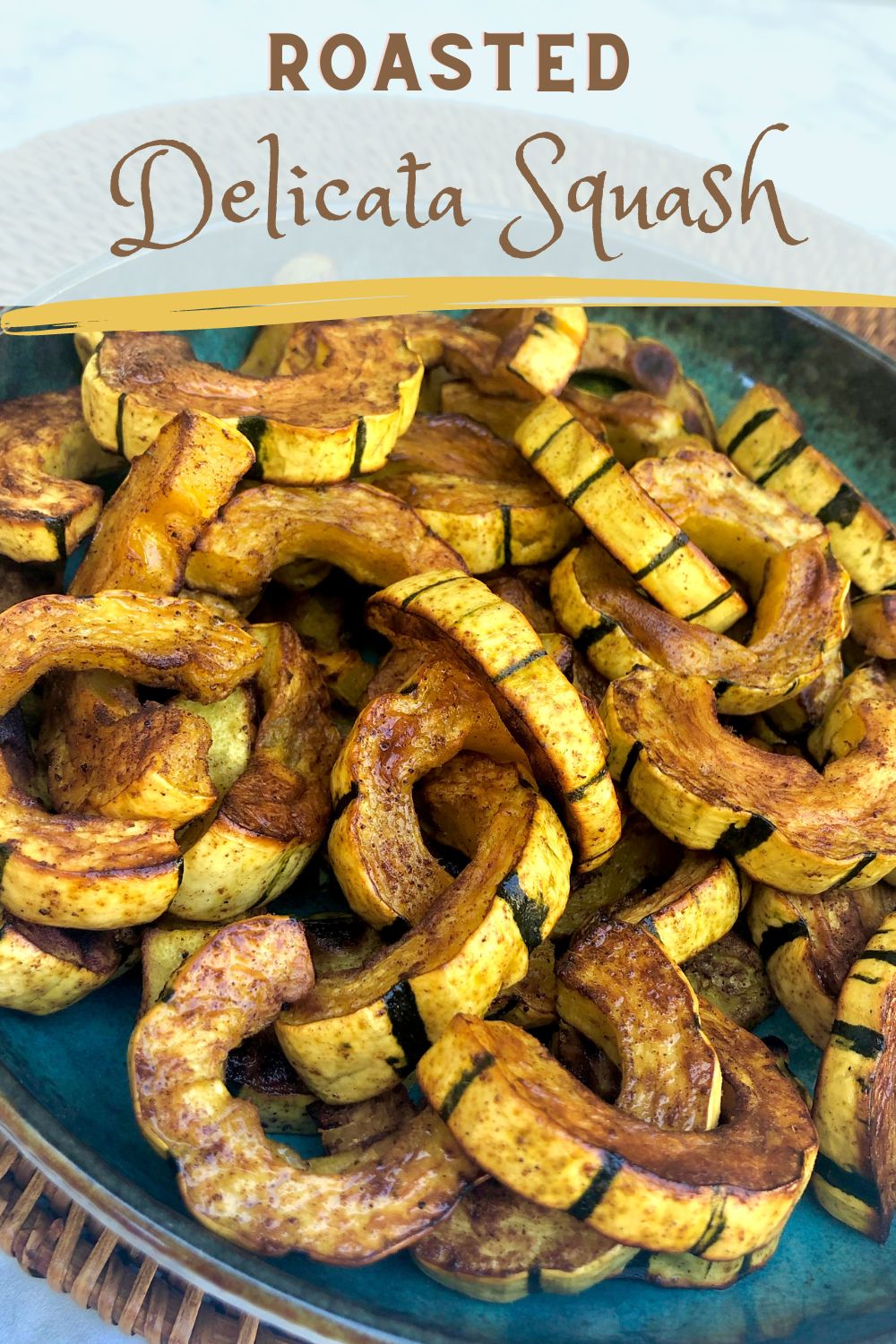Roasted delicata squash half moons on a teal dish.