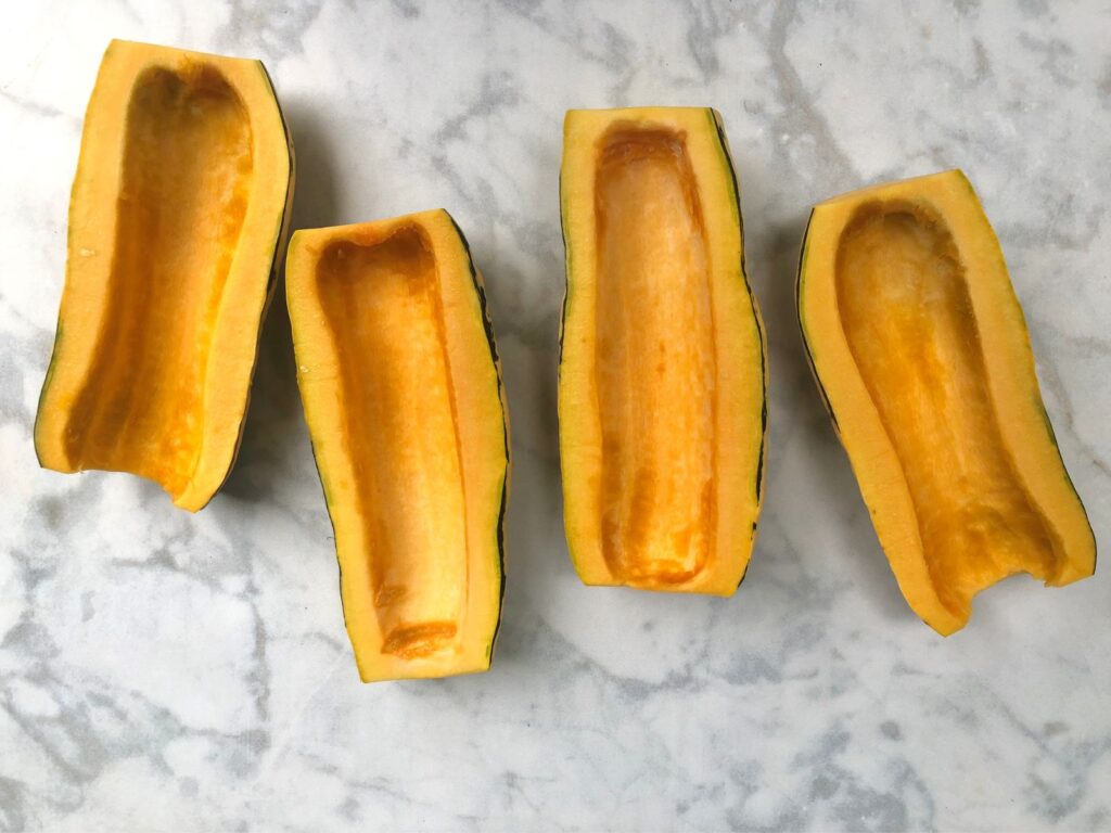 2 halved delicata squash with seeds scooped out.