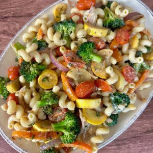Cavatappi pasta with tahini sauce and sauteed vegetables in an oval dish