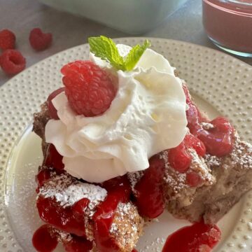 bread pudding topped with raspberry puree and a dollop of whipped topping.