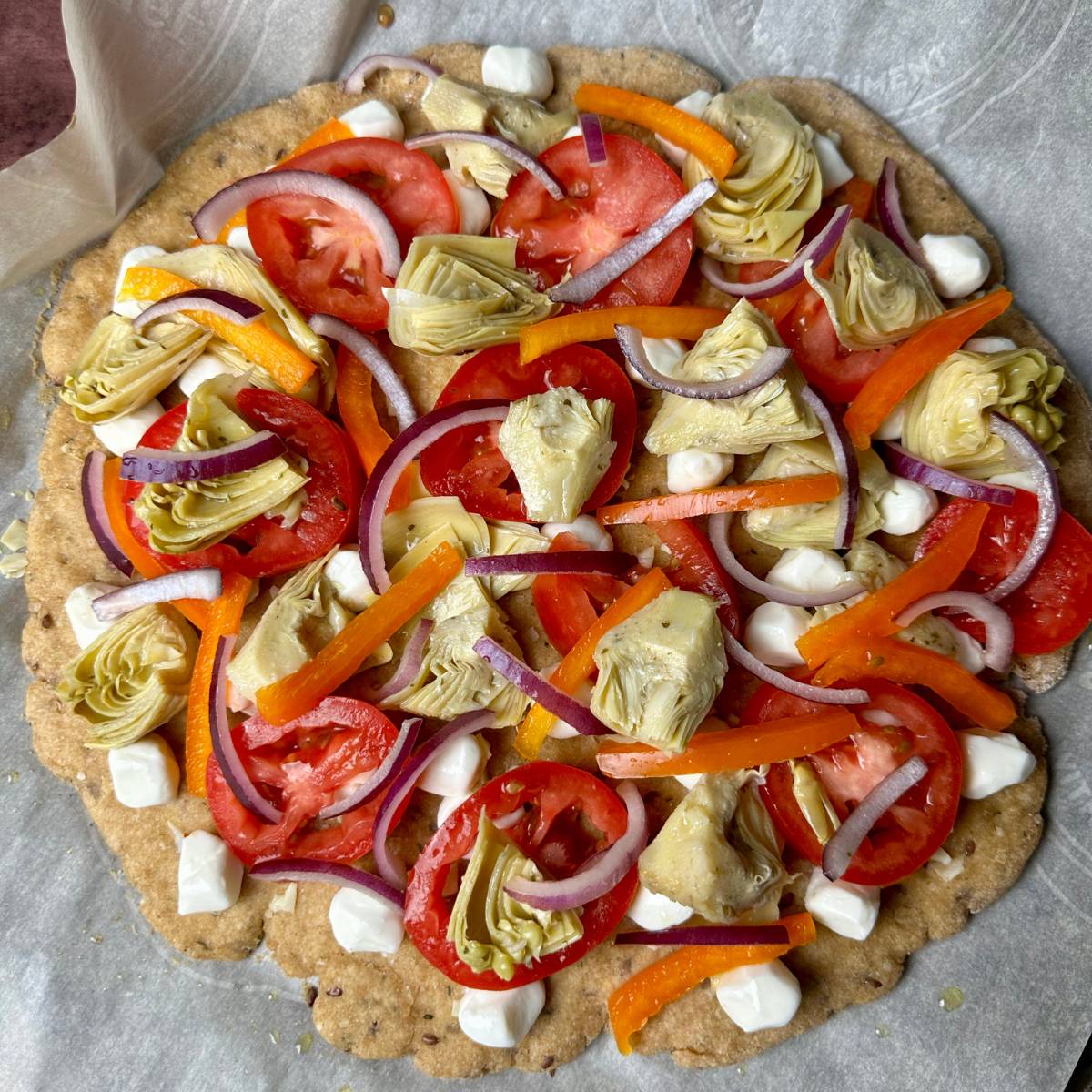 Circular pizza topped with tomato , artichokes, onion, and bell pepper.