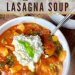 A bowl of lasagna soup with zucchini and spinach with a dollop of creamy ricotta and fresh basil on top.