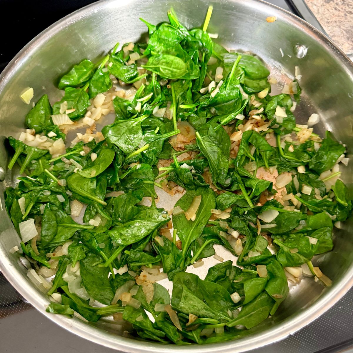 Sauteed spinach, onion and garlic in a skillet.