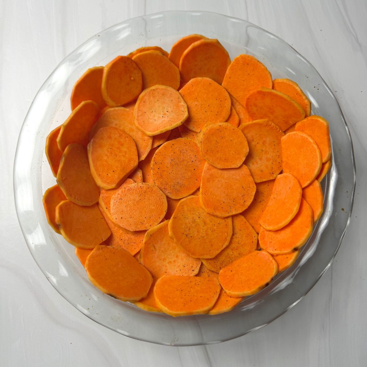 Sweet potato slices arranged in a glass pie plate.