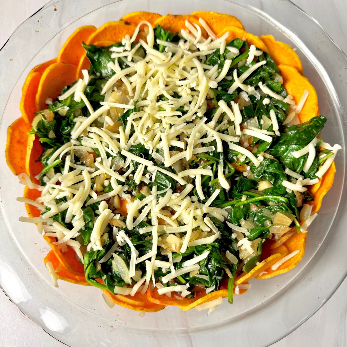 Sweet potato crust quiche with spinach and sprinkled cheese on top.